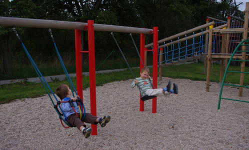 Kloučci se oba najednou houpou na houpačk&aacute;ch.