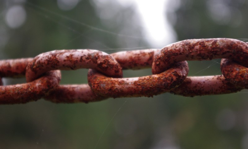 Kr&aacute;sn&yacute; detail řetězu nedaleko ohrady s ovečkami.